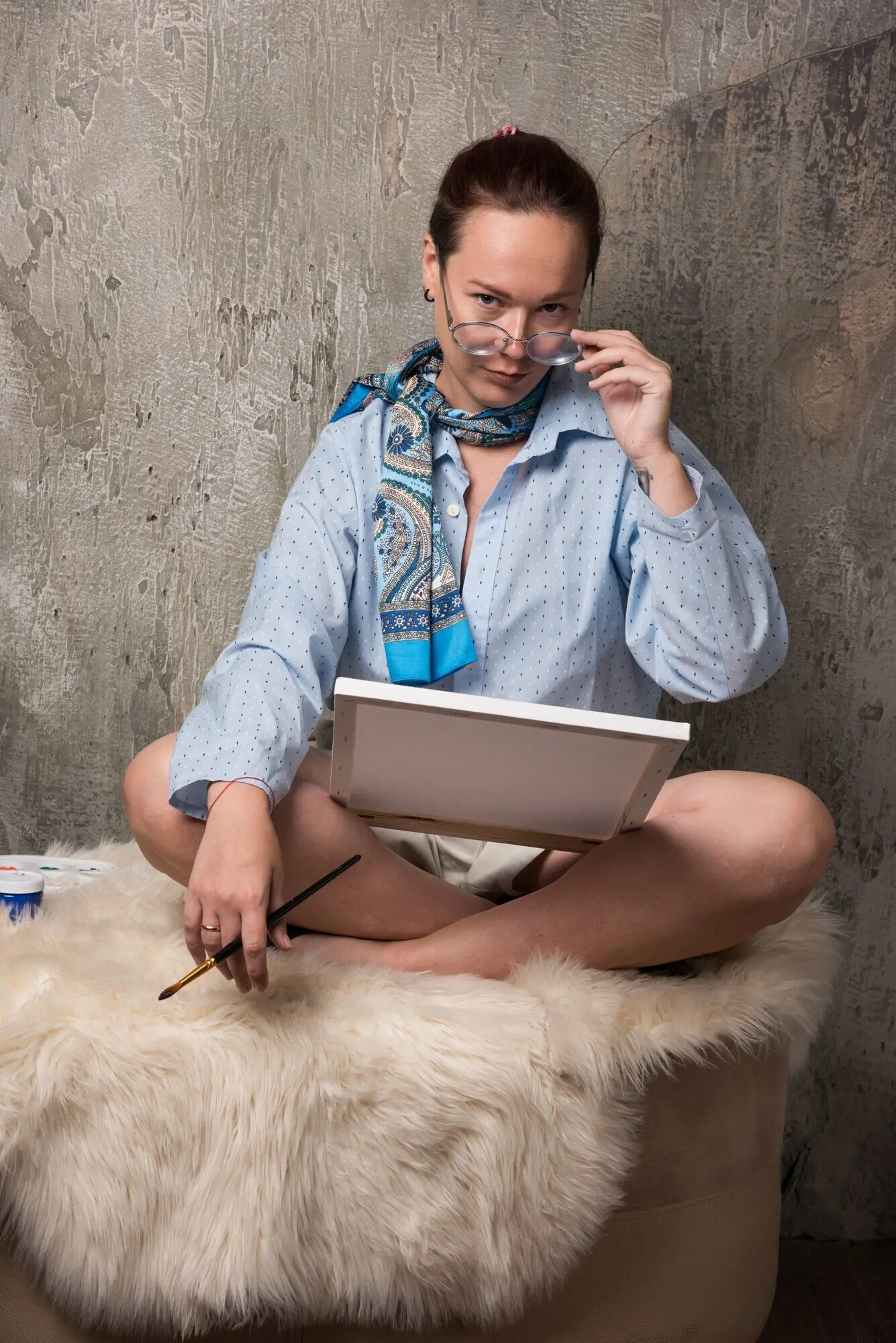 대리석 배경에서 캔버스와 붓을 가지고 앉아 있는 여성. 고품질 사진.