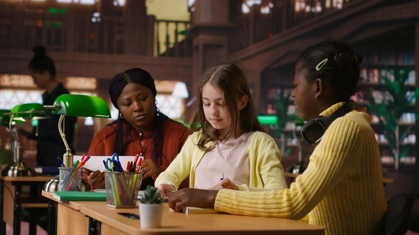 사춘기 이전의 소녀들과 그들의 교수가 도서관에서 학교 과제에 협력하고 있다.